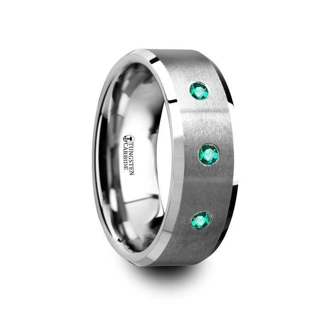 ICARUS Brushed Tungsten Men’s Wedding Ring with Polished Beveled Edges and 3 Emeralds - 8mm Three eye-catching and dazzling Emeralds are prominently displayed in this bold and modern brush-finished Tungsten Carbide men’s wedding band by Thorsten with polished beveled edges. Engraving available! See Pictures for Details. Does Not Delay Order. Includes Thorsten Lifetime and Lifetime Sizing Warranty (excluding re-engraving). Available in an 8mm width. Tungsten Carbide is the newest and strongest metal for jewelry that does not scratch easily. Comfort Fit – domed interior band slides over the knuckle easier with less friction. Brand: ThorstenMetal Type: Tungsten Carbide Color: SilverFinish: Brushed Style: Beveled Stones: Emerald SKU: T5424-BPBE