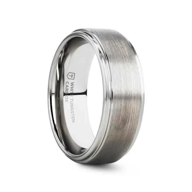 This conservative style white tungsten ring with a raised brush finished center and polished step edges from our White Tungsten Rings line is made especially for couples who love the durability of tungsten and the bright white color of platinum. White tungsten is made by impregnating rhodium, a platinum group metal, into the surface of a tungsten ring. The color is very similar to platinum or white gold, which is whiter in color than normal tungsten. This unique bonding process makes the platinum much more scratch resistant than the plating on white gold wedding bands. This is the perfect wedding band because it combines the best of both worlds. Re-sizing and Warranty on all Thorsten alternative metal rings, no exchange or sizing fees, compared to our competitors. Brand: Thorsten Metal Type: Tungsten Carbide Color: White Finish: Brushed Style: Flat|Raised Center Stones: None SKU: W687-RBCW